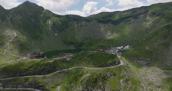 aerial movement towards a green valley in mountains with tourists