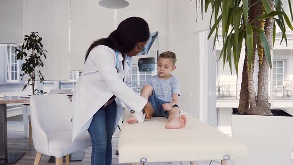 Young Female Doctor Bandaging Leg of Little Patient