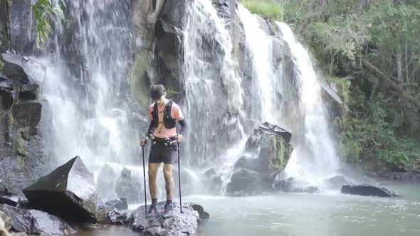 Male hiker with trekking poles in forest