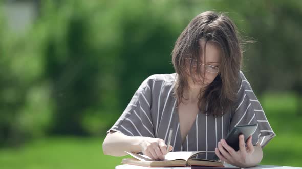 Tired Woman is Reading Book in Park Putting Off Glasses and Massaging Face