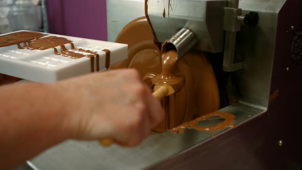 Worker filling mould with melted chocolate