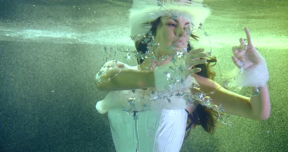 Fairy of Christmas Is Swimming Underwater and Playing with Star Garland, Magic Shot