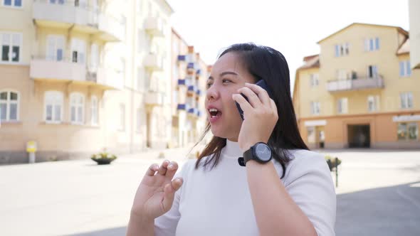 Close up of Asian woman on the street in town and calling. Using social network on smartphone