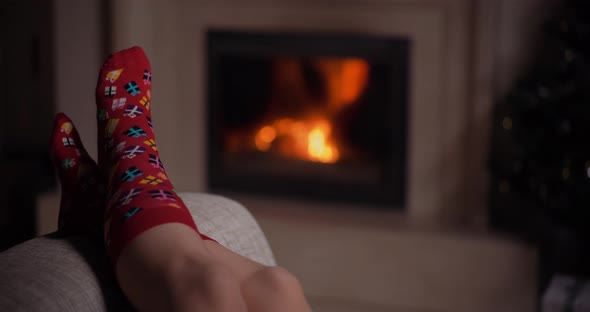Woman Wearing Warm Wool Socks Lying By the Fireplace at Christmas