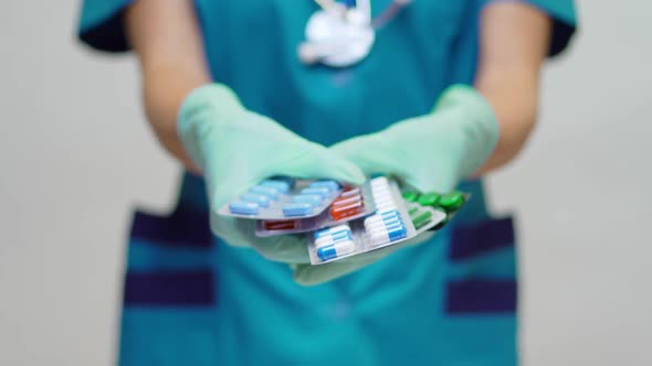 Medical Doctor Nurse Woman Wearing Protective Mask and Rubber or Latex Gloves - Holding Pills