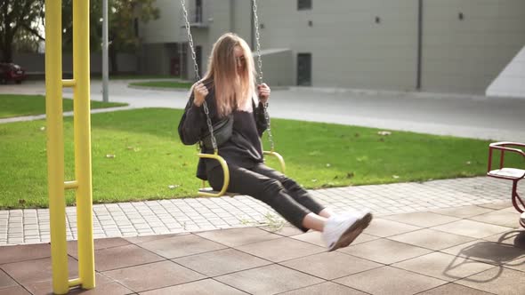 Long Haired Woman Swinging on a Swing in the Green Park Calmly