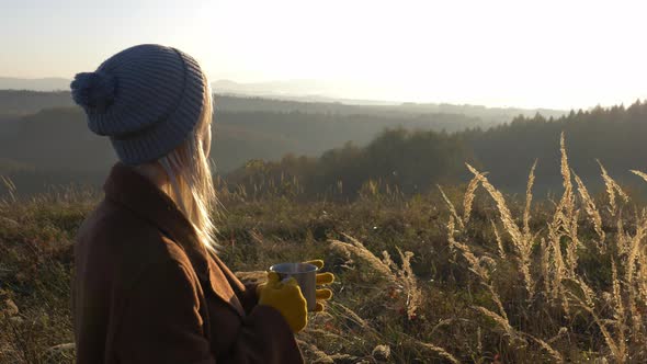 woman hold mug of tea in mountains Sudetes in November in sunset