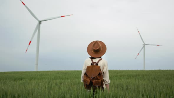 Portrait of a young girl with a backpack looking at the wind turbines