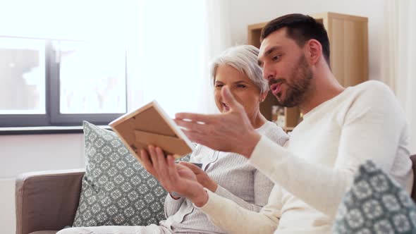 Adult Son and Senior Mother with Photo at Home