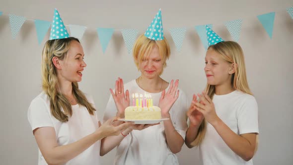 Happy Girl with Sister and Mom Celebrate Birthday By Blowing Out Candles on Cake and Clapping Hands