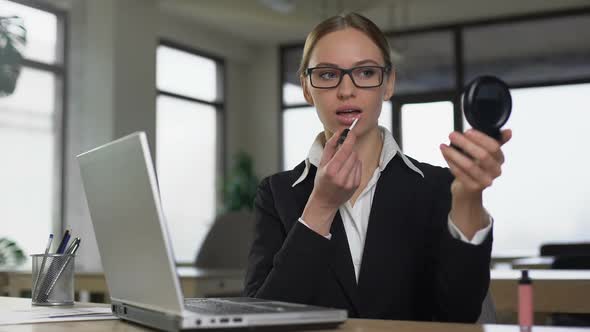 Woman Applying Lipstick in Workplace, Concept of Dress and Appearance Code