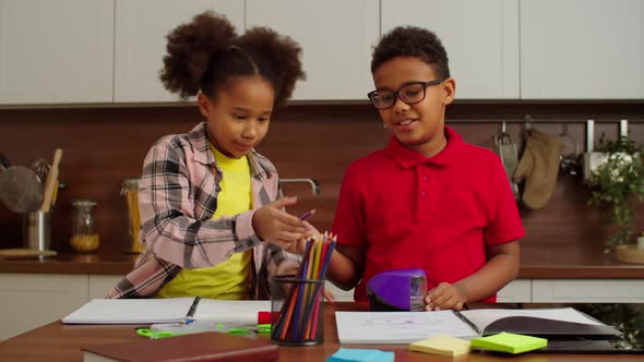 Adorable Preadolescent Black Boy Sharpening Pencils During Drawing Indoors