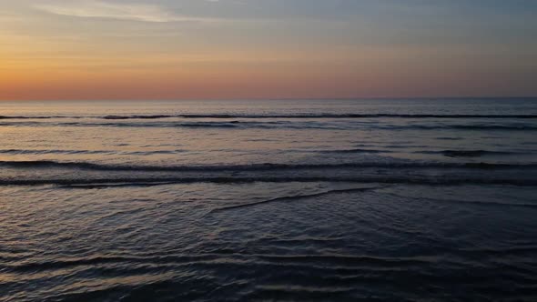 A picturesque sunset by the sea in summer. Waves roll ashore