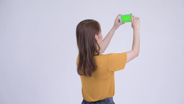 Rear View of Young Asian Woman Taking Picture with Phone