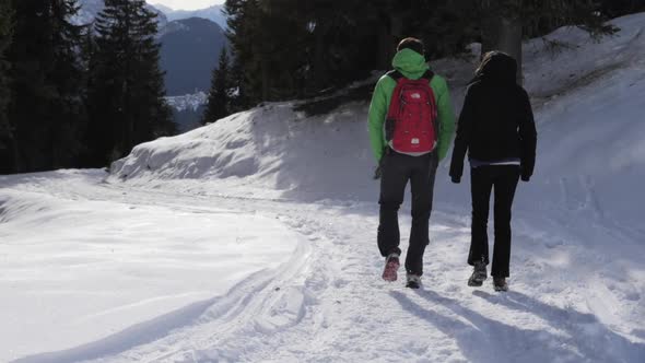 A man and woman couple hiking in the snow in mountains in the winter