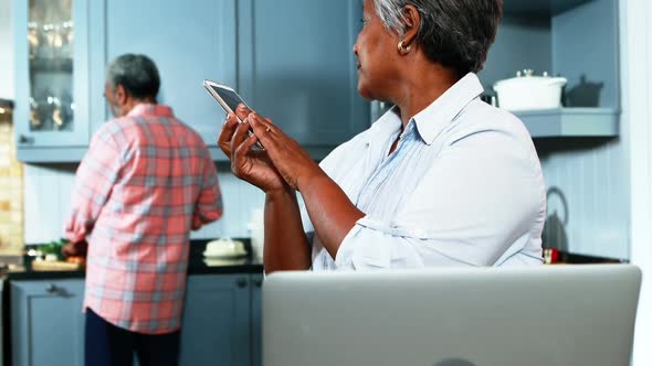 Senior couple talking on mobile phone in kitchen