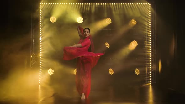 A Young Girl Dancer in a Red Sari, Indian Folk Dance, Shot in a Dark Studio with Smoke and Yellow