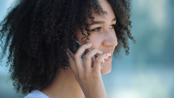 Young Attractive African American Woman Talking on Mobile Phone Outdoors, Making an Order or