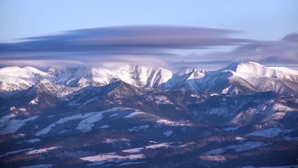 Snowy mountain peaks. The clouds spill over the mountain tops. Winter  landscape