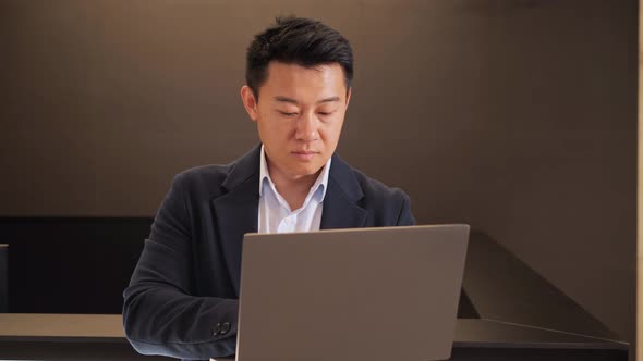 Asian Male Executive Typing Work Email on Computer Laptop in Lobby Place