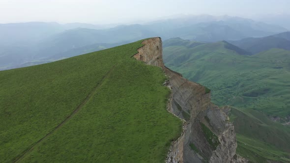 Aerial Shot of Rocky Cliff Covered By Green Field