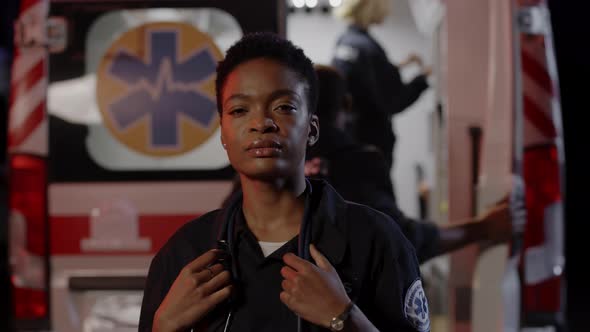 African American Paramedic Standing on Street with Ambulance Behind