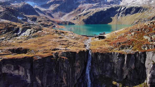 Waterfall Flowing Down On Mountain Cliff From Weisssee Reservoir In Austria. - aerial