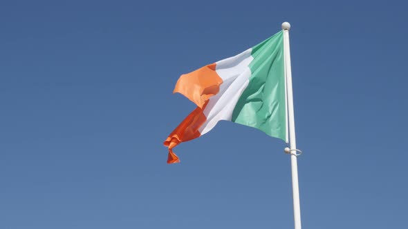 National symbol of Ireland against blue sky 4K 2160 30fps UHD footage - Irish tricolour flag fabric 