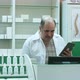 Senior Pharmacist with Mustache Working on Tablet Pc Checking Medicine in Pharmacy - VideoHive Item for Sale
