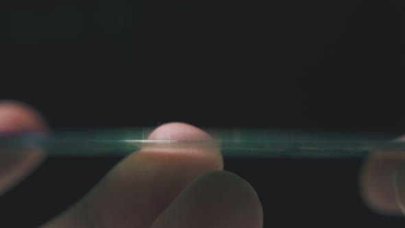 Man Holds Shining Compact Disc on Finger in Dark Background