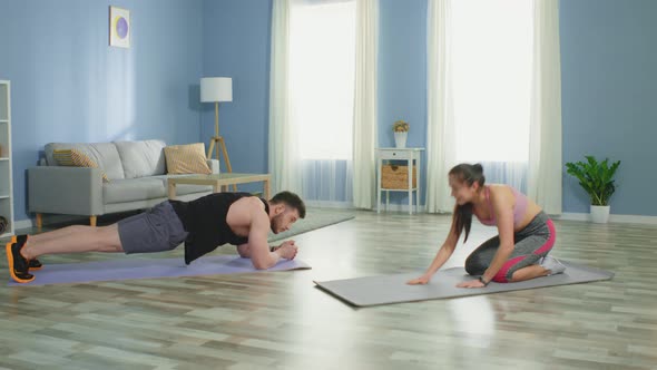 Man and Woman Stand in Elbow Plank and Have Fun at Home