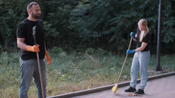 Volunteers Sweeping Dirt and Dry Leaves with a Broom at a Local Park