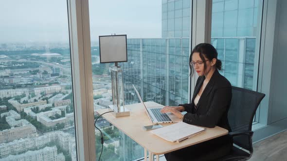 Business Woman Works in a Modern Office Located on a High Floor of a Skyscraper. Attractive Girl