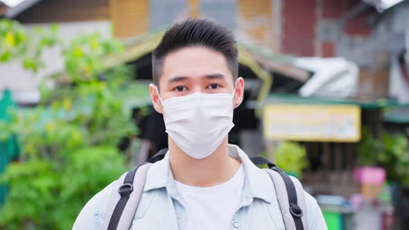 Portrait of Asian attractive male backpacker wear mask travel in city on holiday vacation.