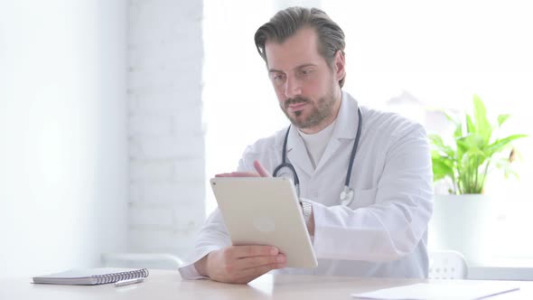 Young Doctor Using Tablet While Sitting in Clinic