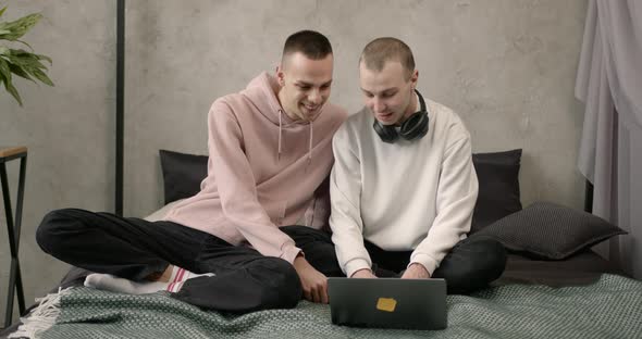 Gay Couple Consulting Their Travel Plans Together with a Laptop