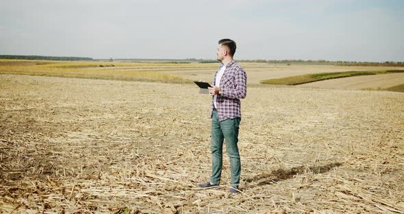 Young Farmer Stand on Field Agriculture and Use Digital Tablet