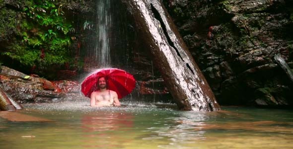 Man With Umbrella At Waterfall In Borneo