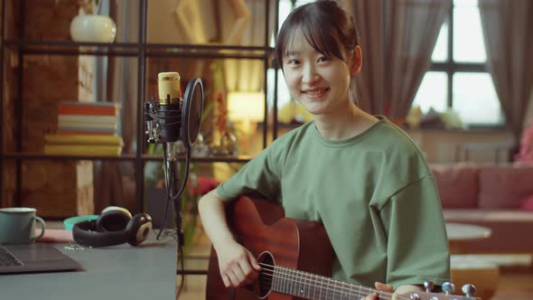 Portrait of Asian Woman with Guitar at Home Recording Studio