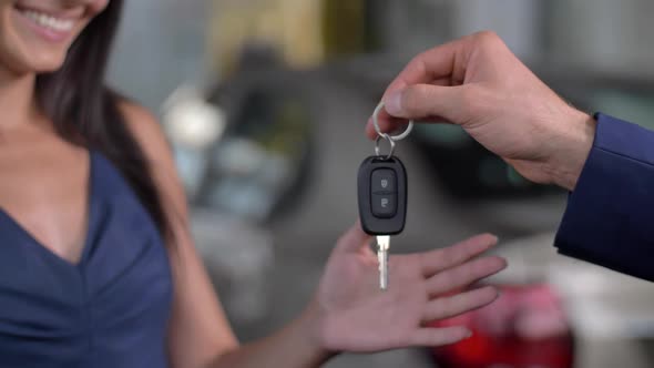 Hand of Auto Dealer Giving Car Key To Woman Buyer