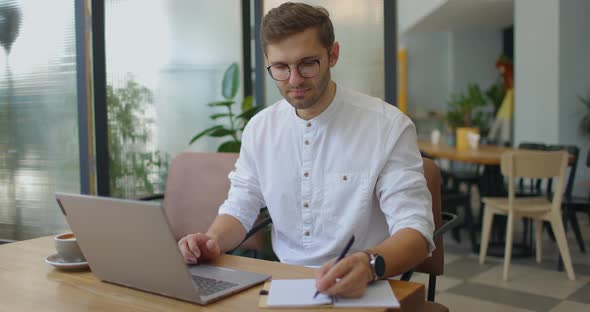 Young Man Working with Laptop in Coffee Shop