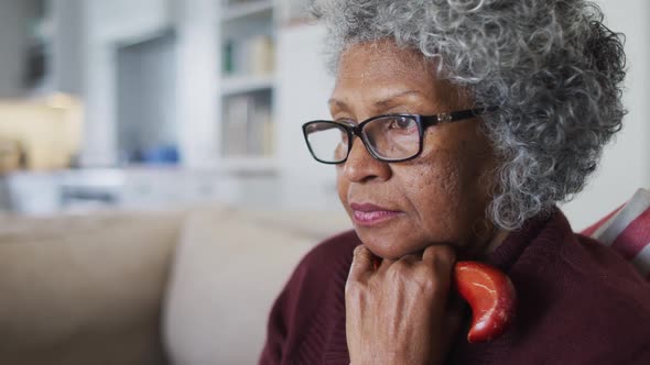 Thoughtful senior african american woman holding walking stick sitting on the couch at home