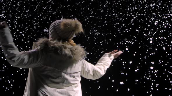 Bottom View of a Happy Young Woman in a Hat and Warm Clothes Whirling Among the Falling Snow. Large