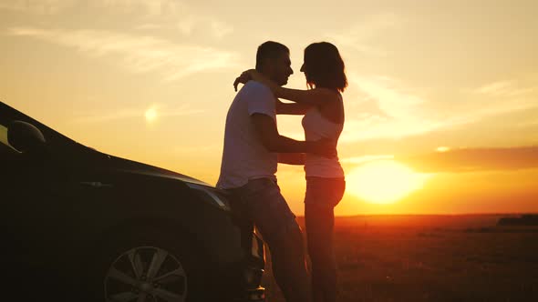 Beautiful Young Couple Standing Near Car on Sunset