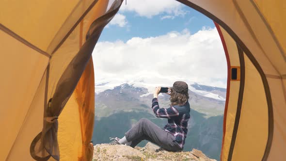 Happy Woman Tourist Takes Pictures on the Phone of Beautiful Views in the Mountains the View From