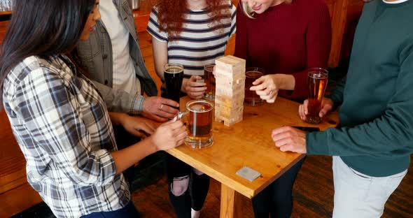 Group of fiends playing jenga while having beer 4k