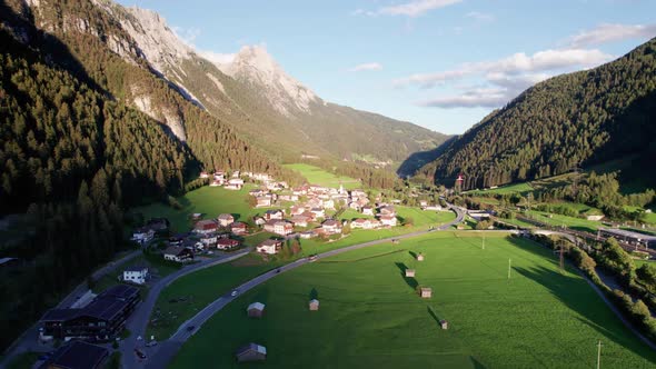 Aerial View of an Austrian Village in a Green Mountain Valley at Sunset Alps