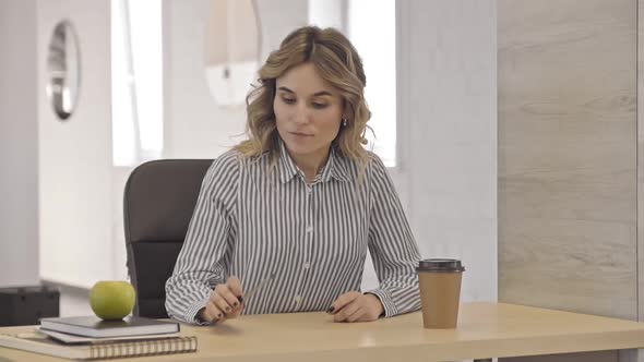 Business Woman Sitting at Table Holding Pencil and Looking Posing at the Camera Irrl