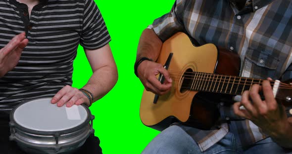 Mid section of male musicians playing guitar and drum