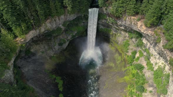 Aerial Pan Up Large Earth Crater To Epic Waterfall With Green Foliage In Canada